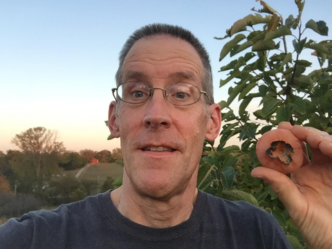 Daniel Kostka owner portrait holding a persimmon